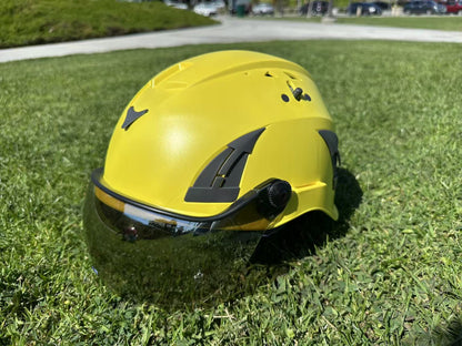 Front side view of AeroPro Yellow ANSI/ISEA Z89.1-2014 Type 1 Class C Safety Helmets with Smoke Visor used for Industrial, Rescue & fall protection sitting on grass. 
